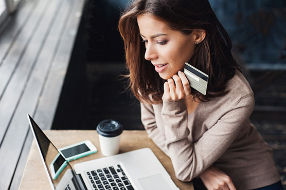 Hispanic woman using a credit card at a laptop