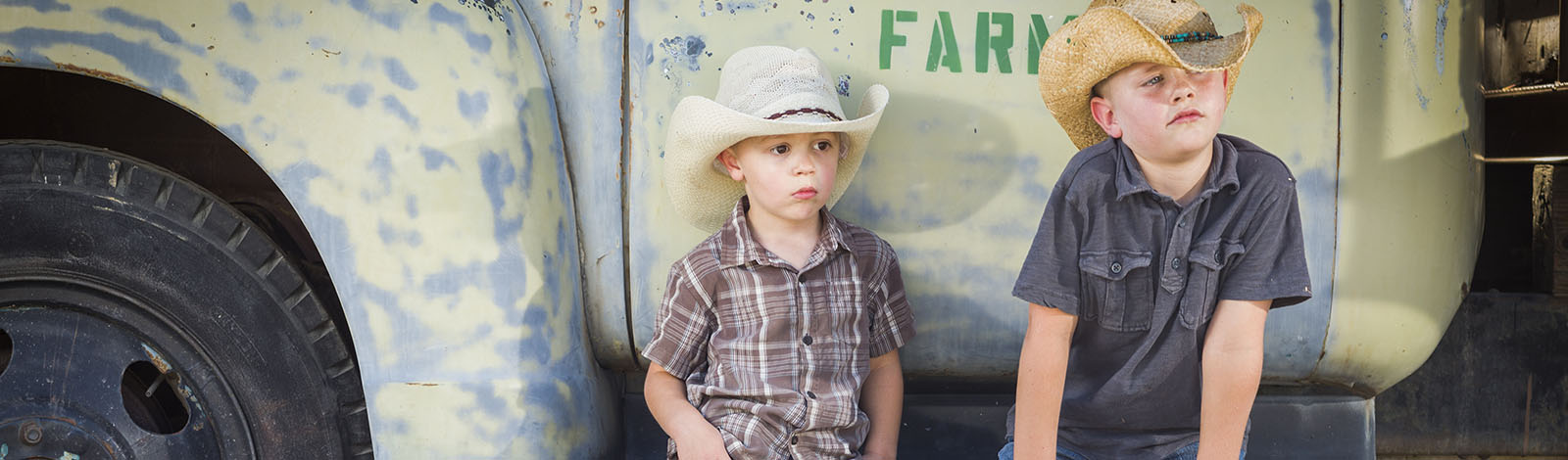 young boys with hats sitting on farm truck